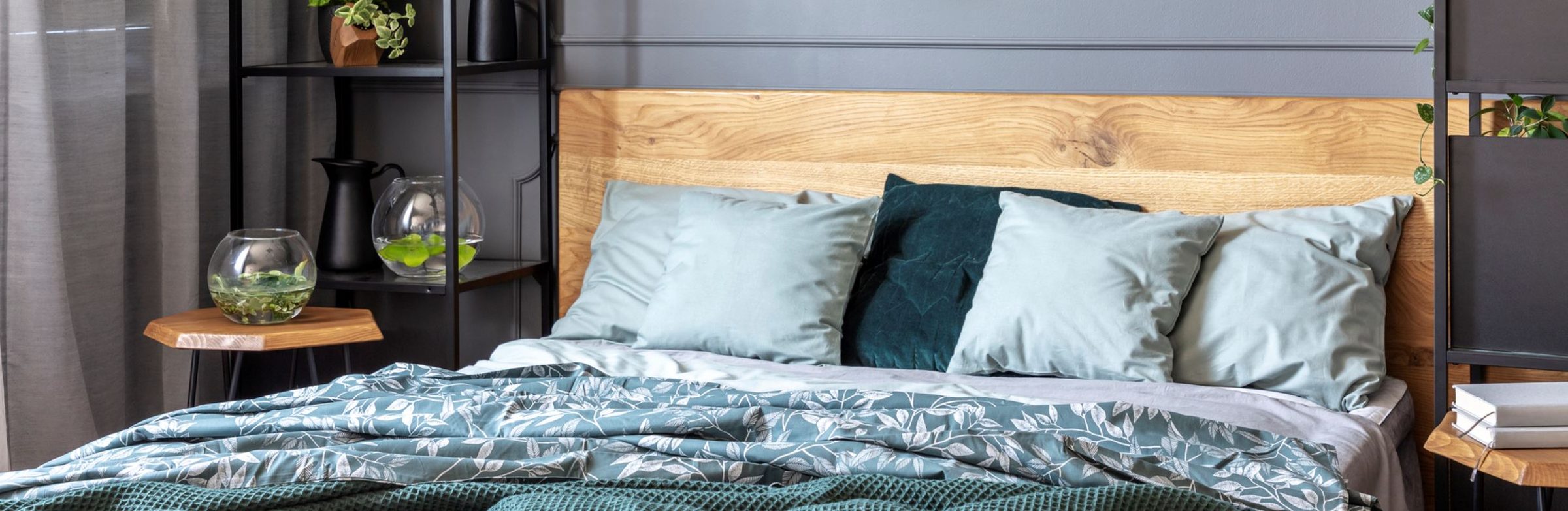 Schlafzimmer mit Holz-Kopfteil und Bettwäsche in Petrol