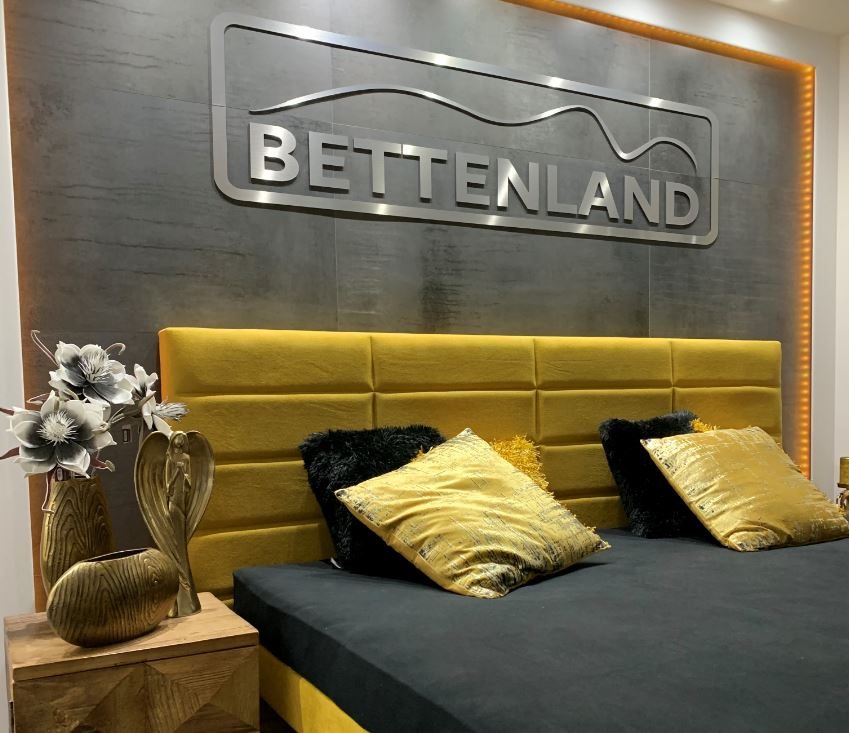 Bett mit gelbem Polsterkopfteil im Bettenland-Showroom